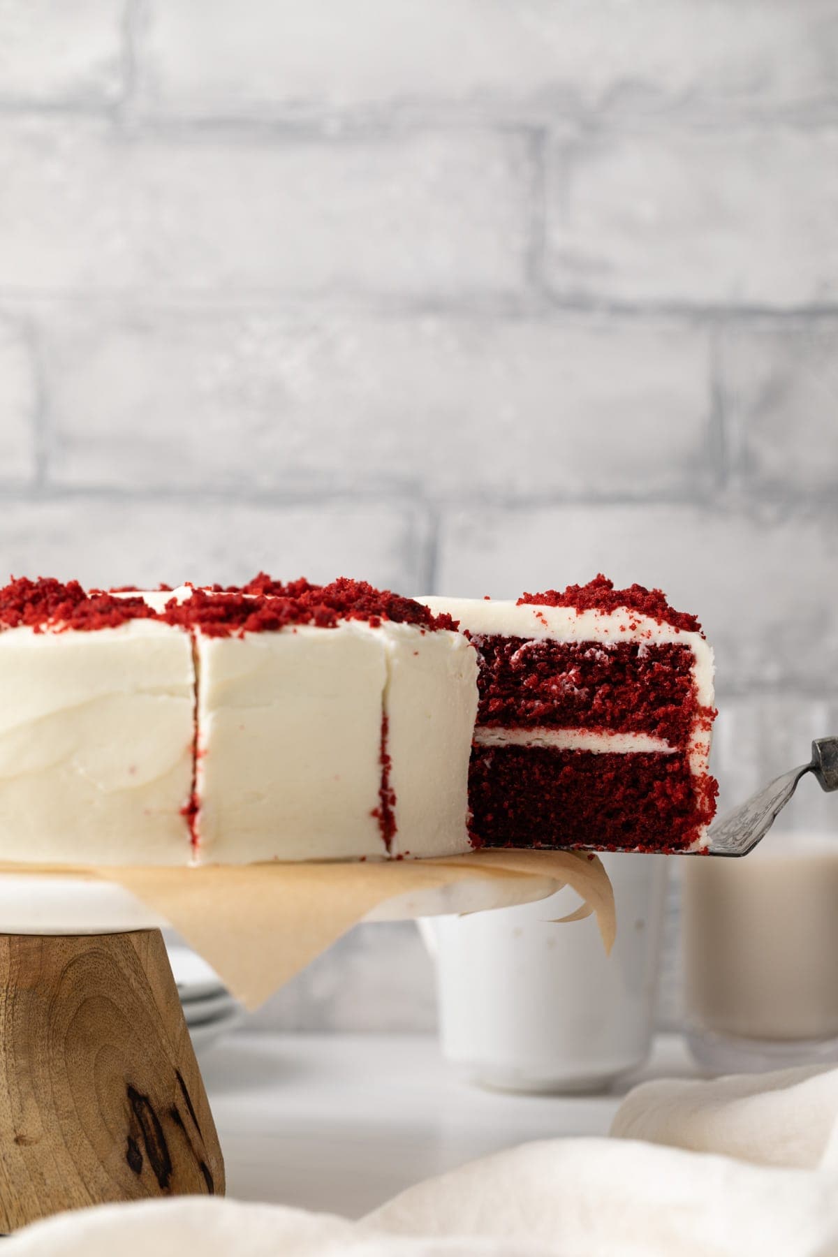 Slice being taken out of red velvet cake with cream cheese frosting.