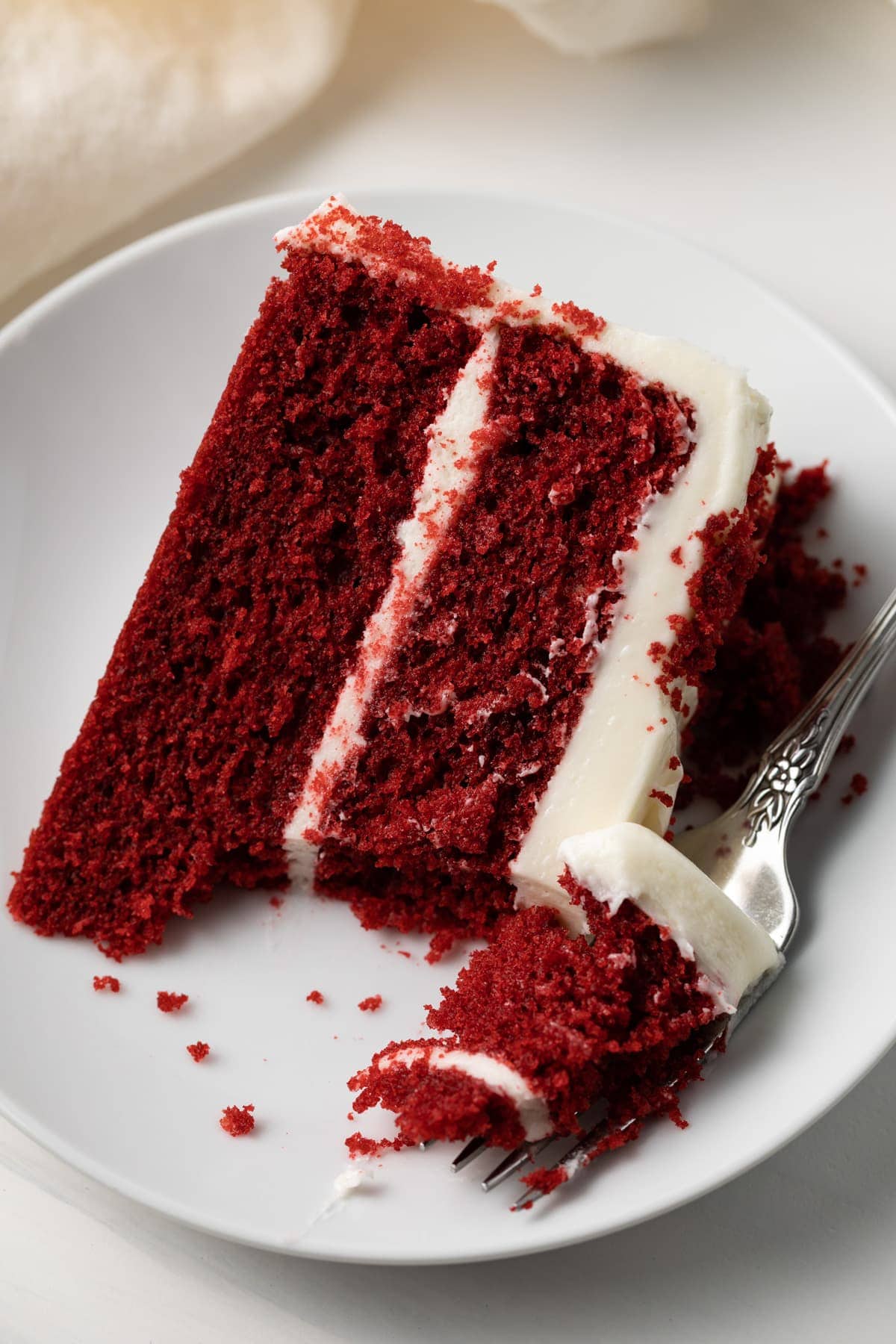 Slice of red velvet cake with a fork taking a bite out.