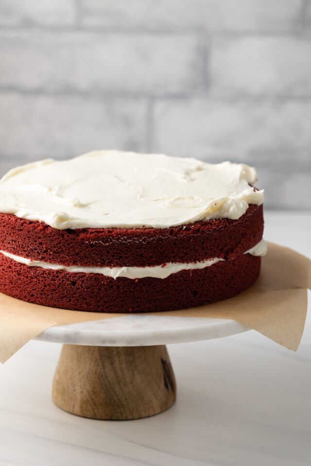 Side view of layered red velvet cake with icing.