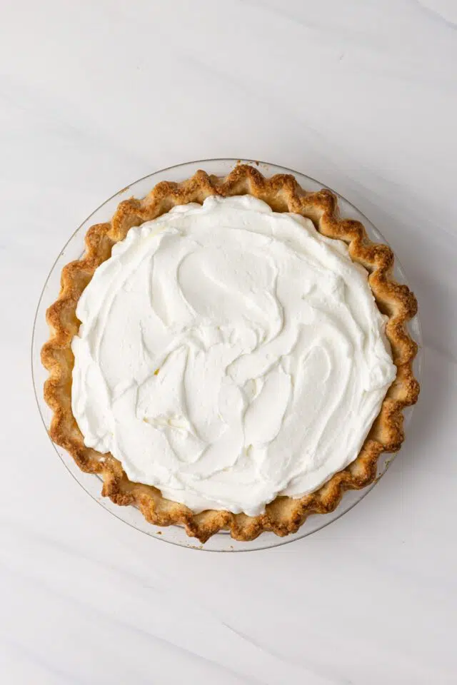 Coconut cream pie topped with whipped cream.