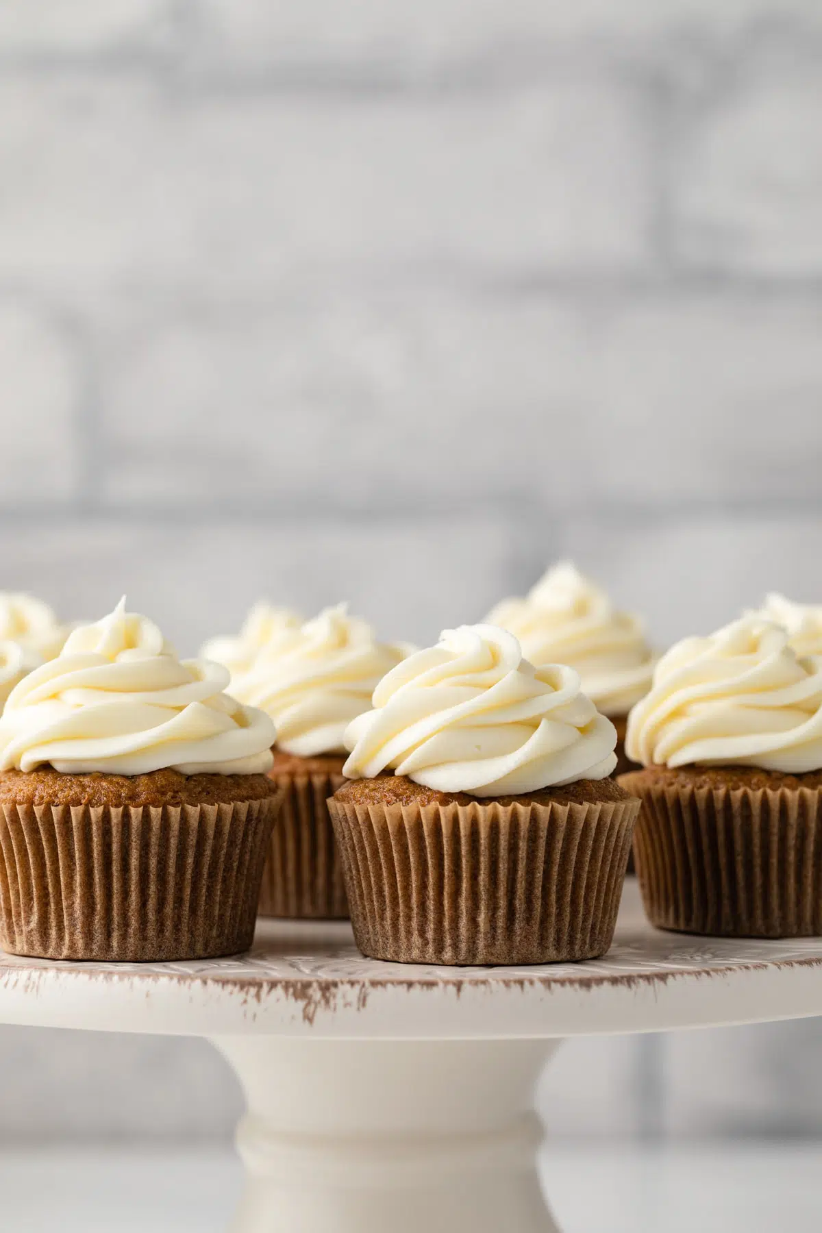 Side view of carrot cake cupcakes on cake stand.