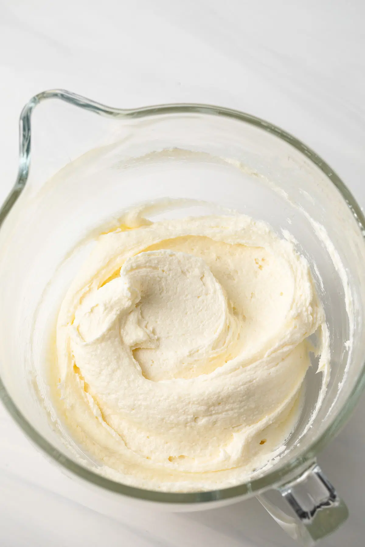 Whipped butter, cream cheese, and sugar in a glass bowl.