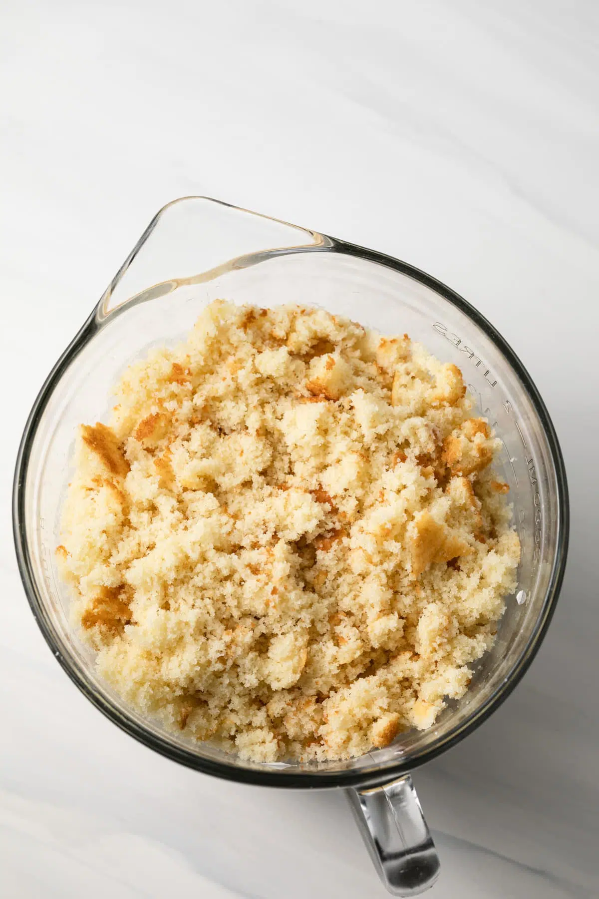 Crumbled cake over frosting in glass bowl.