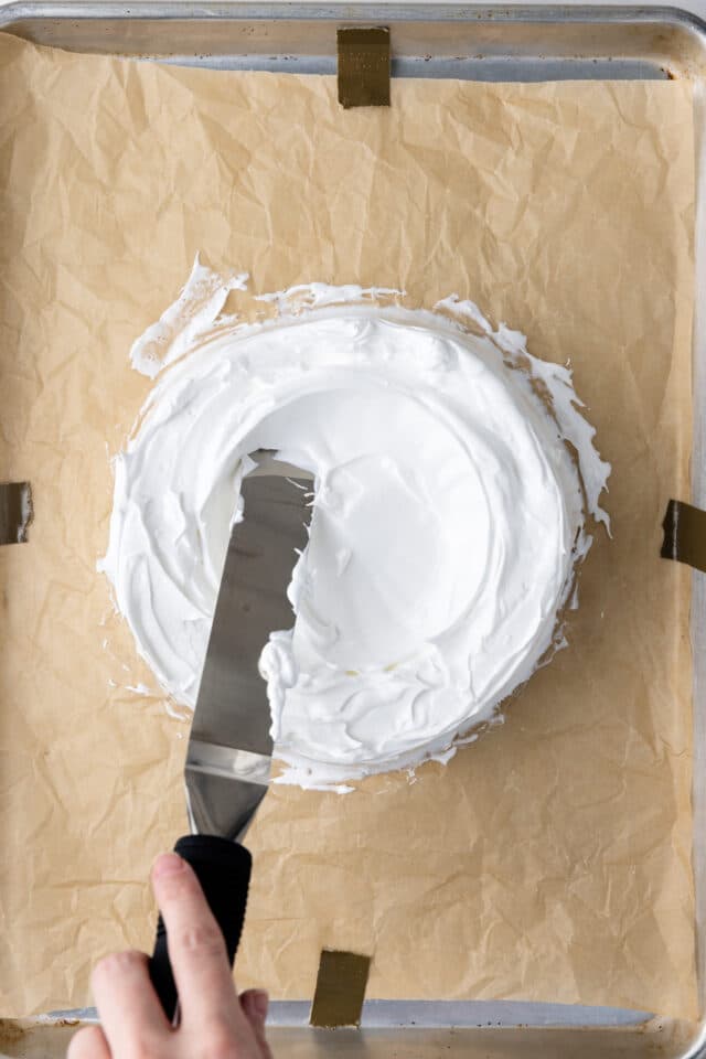 Removing meringue from center of pavlova.