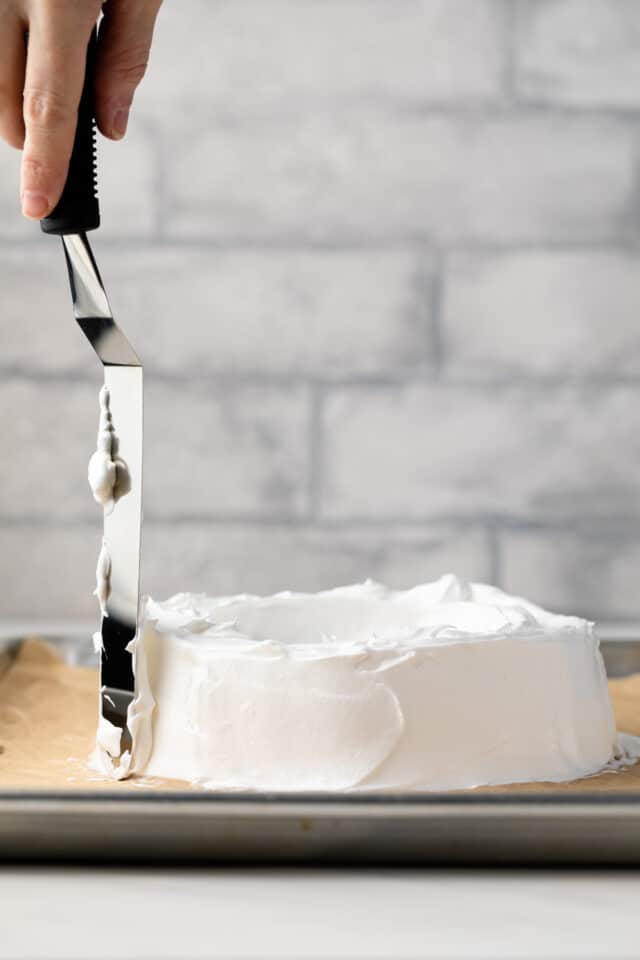 Smoothing meringue in a baking sheet with spatula.