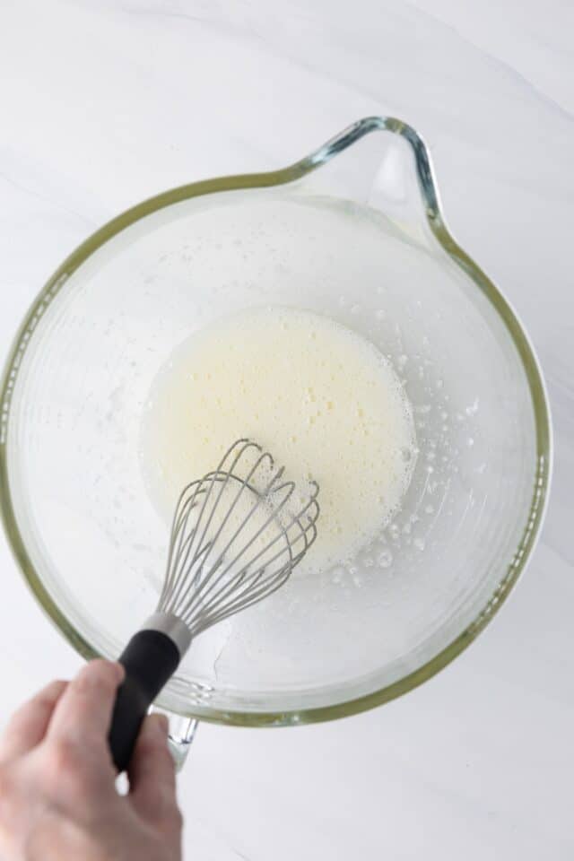 Egg whites in glass bowl with sugar.