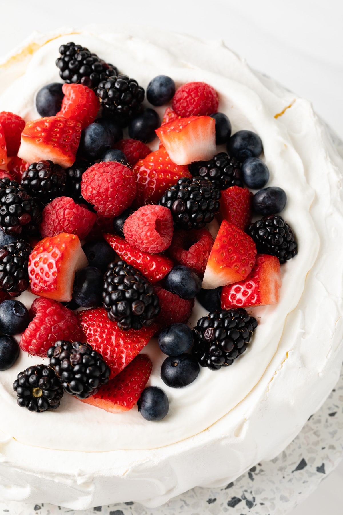 Pavlova topped with whipped cream and berries.