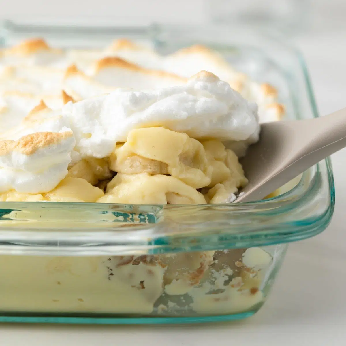 Spooning banana pudding out of a dish.