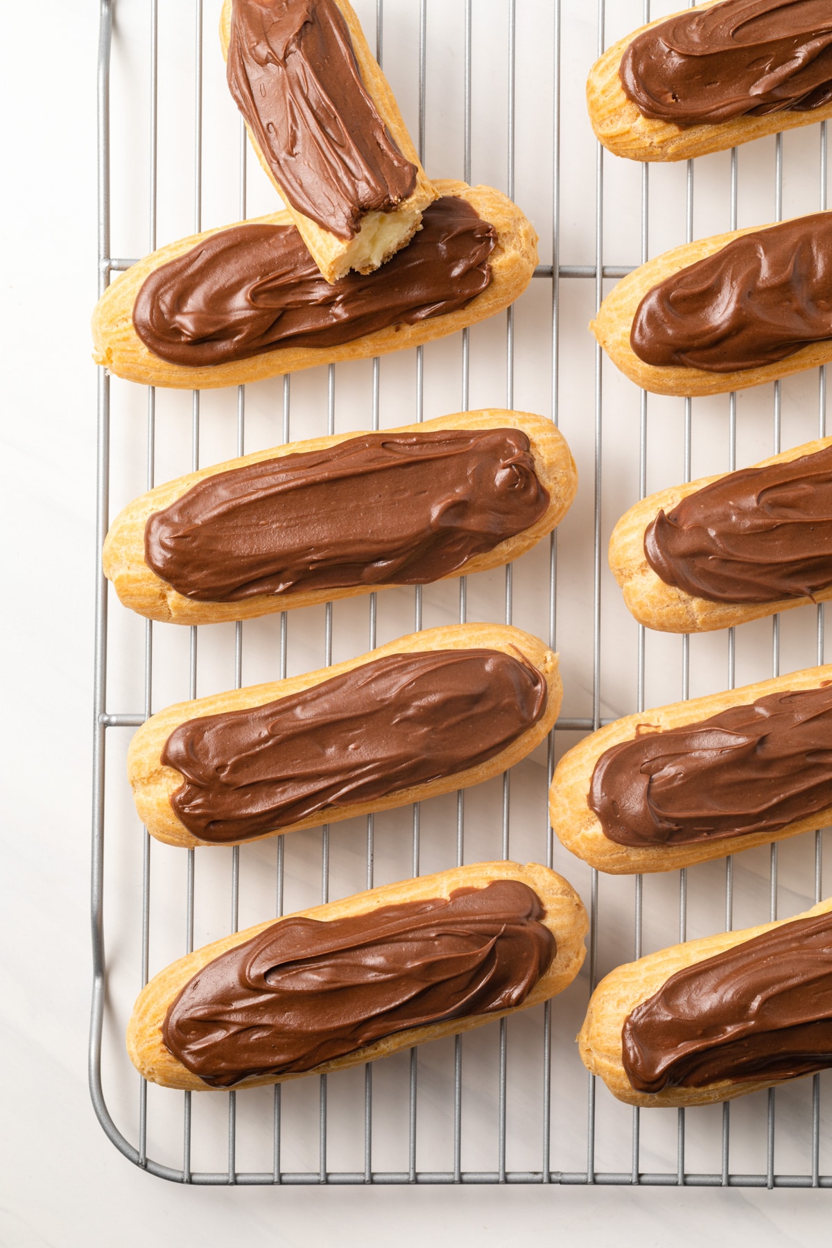 Overhead of classic chocolate eclairs on wire rack.
