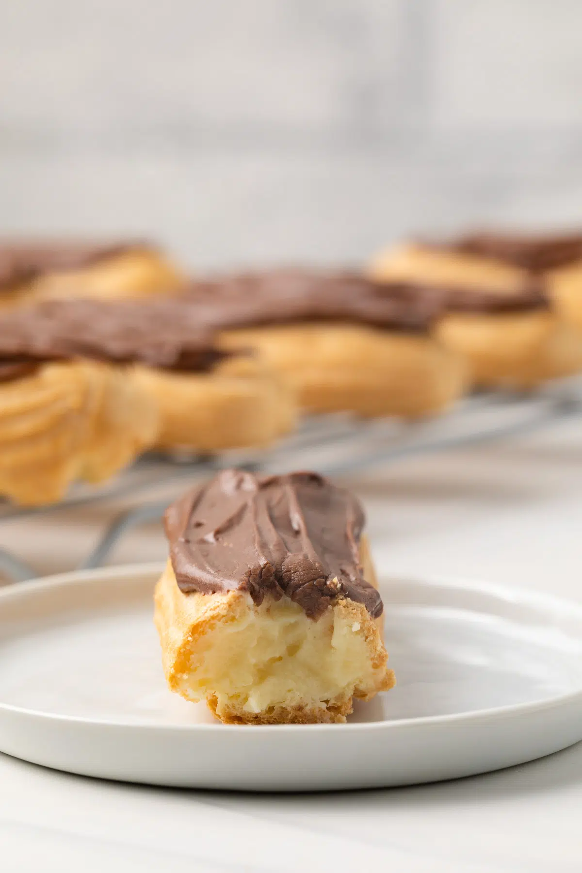 Chocolate eclair on plate with bite take out.