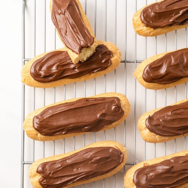 Overhead of classic chocolate eclairs on wire rack.