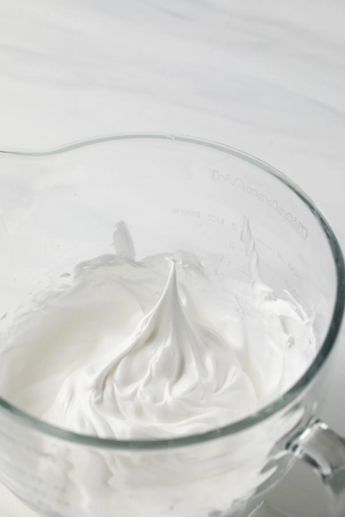 Whipped egg whites in glass bowl.