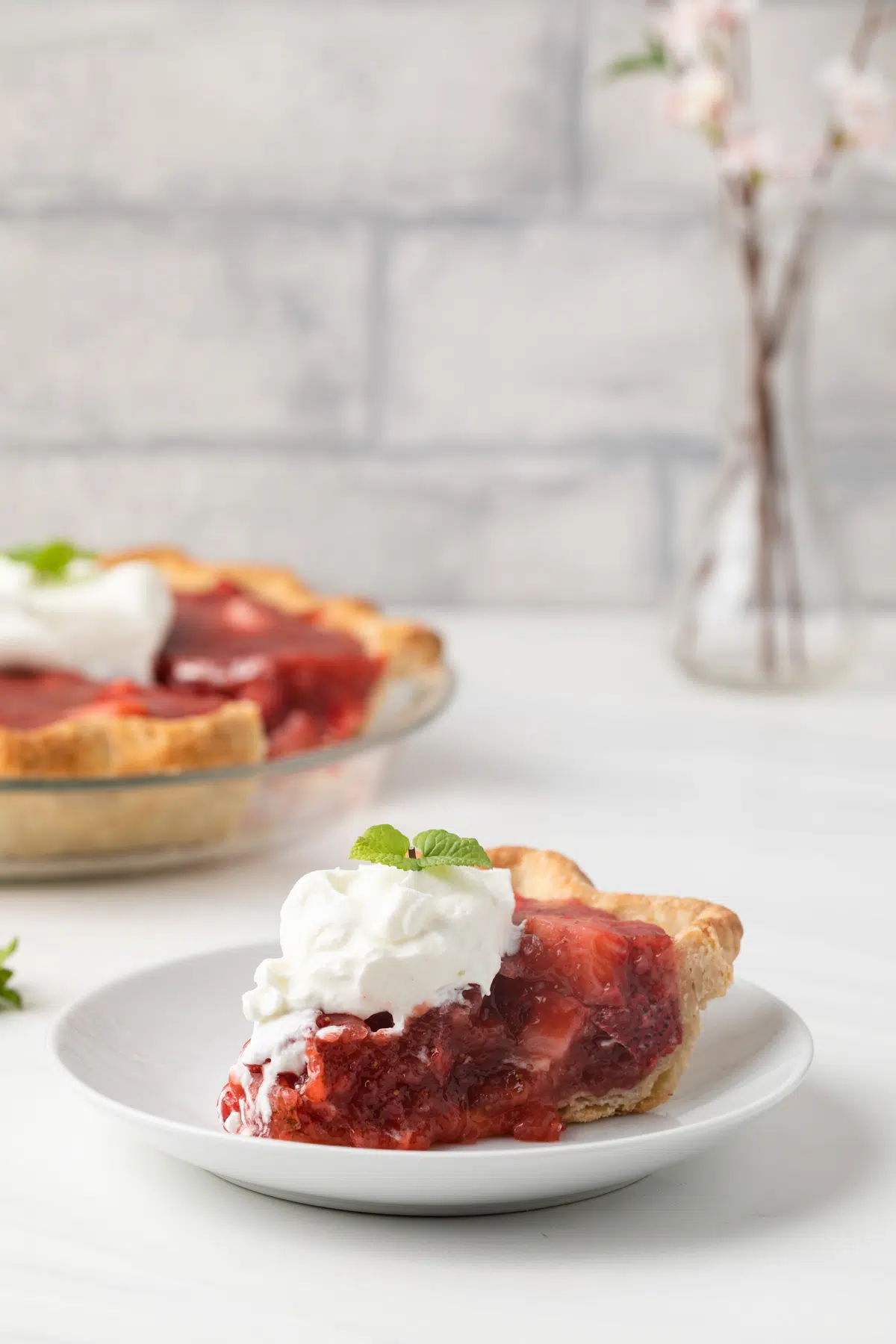 Slice of strawberry pie on white plate.