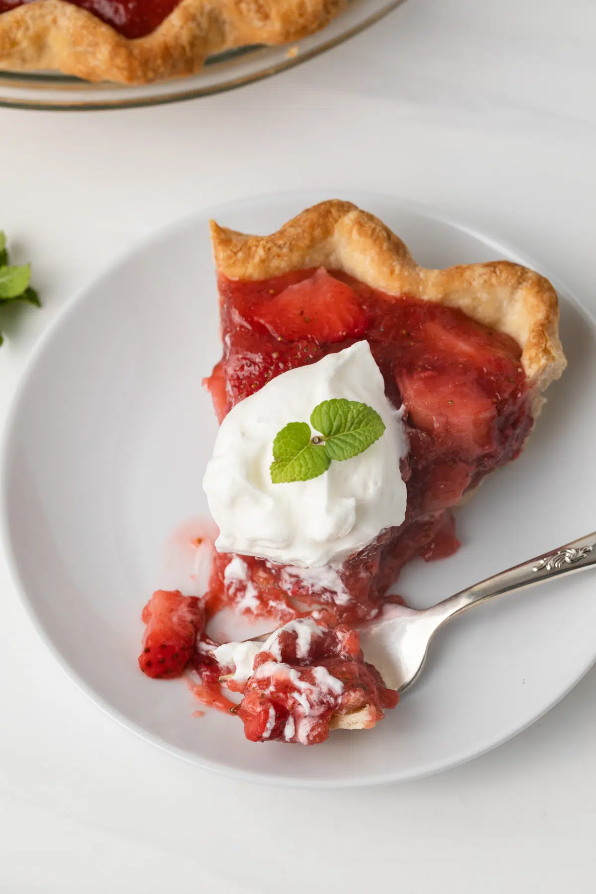 Fork taking a bite out of strawberry pie slice.