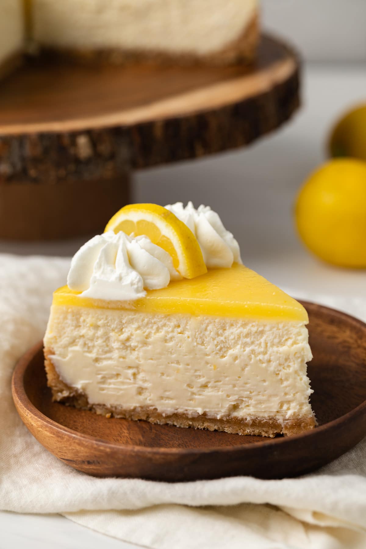 Side view of lemon cheesecake slice on wooden plate.
