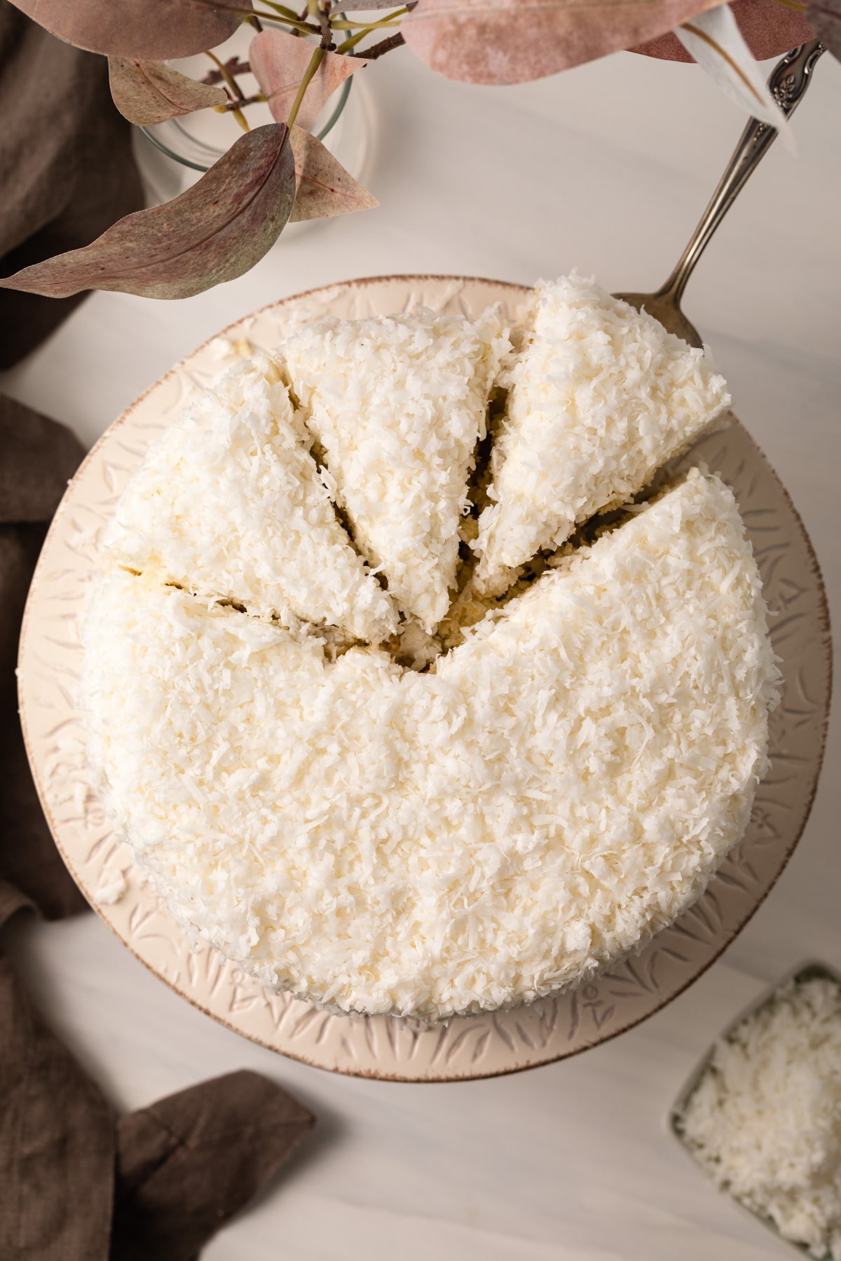 Overhead view of coconut cake with slices cut out.