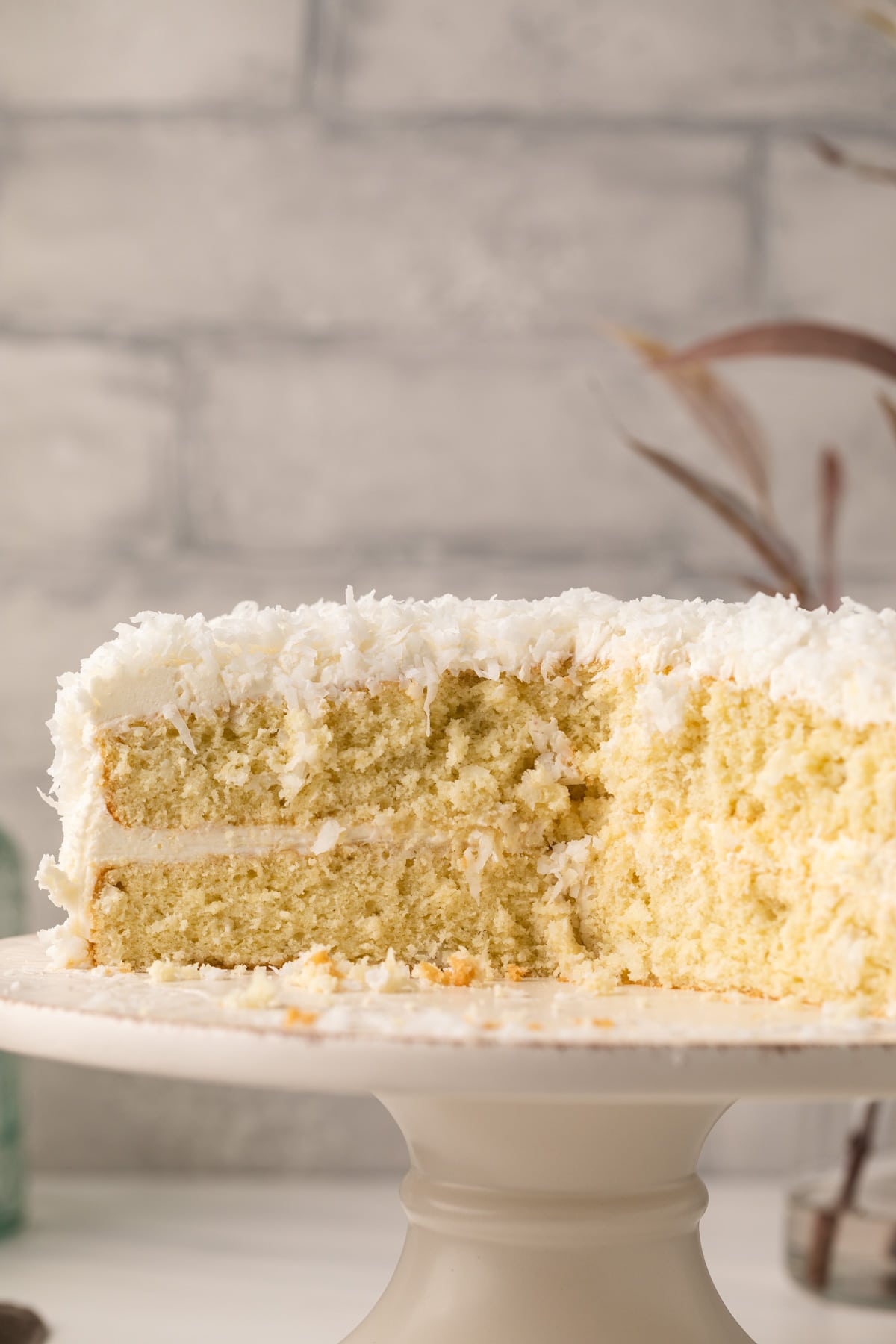 Side view of coconut cake with slices missing.