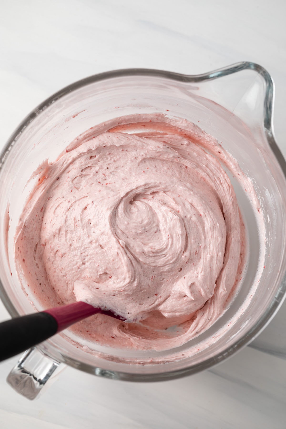 Strawberry buttercream frosting in a glass bowl.