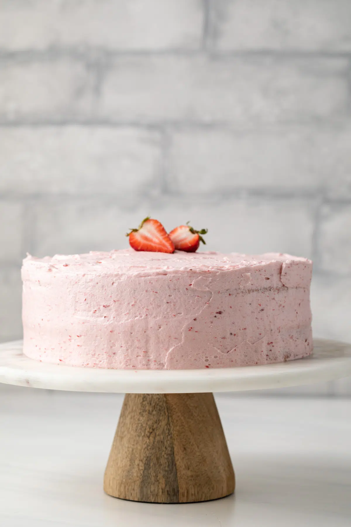 Whole strawberry cake on a cake stand.