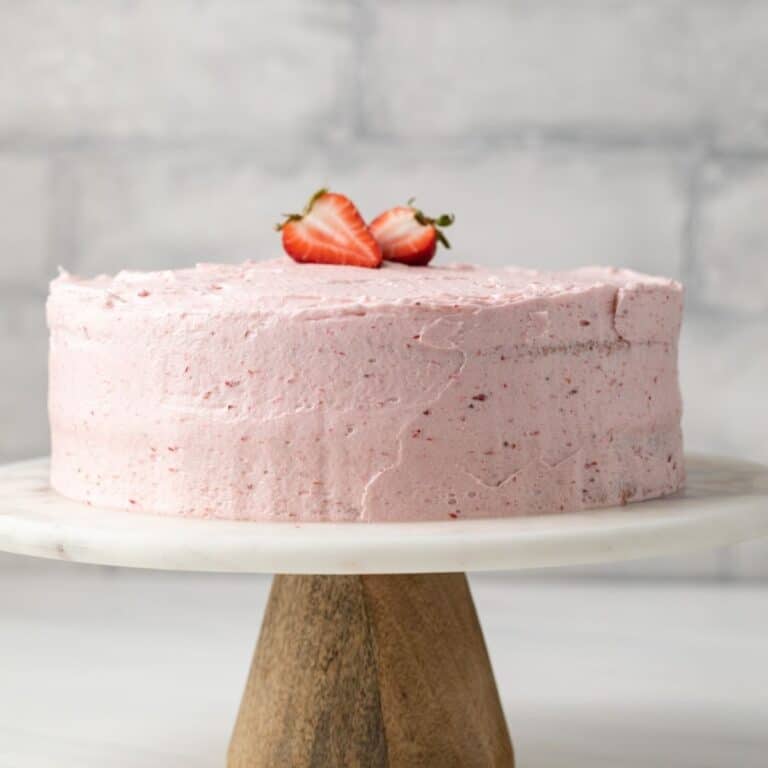 Whole strawberry cake on a cake stand.