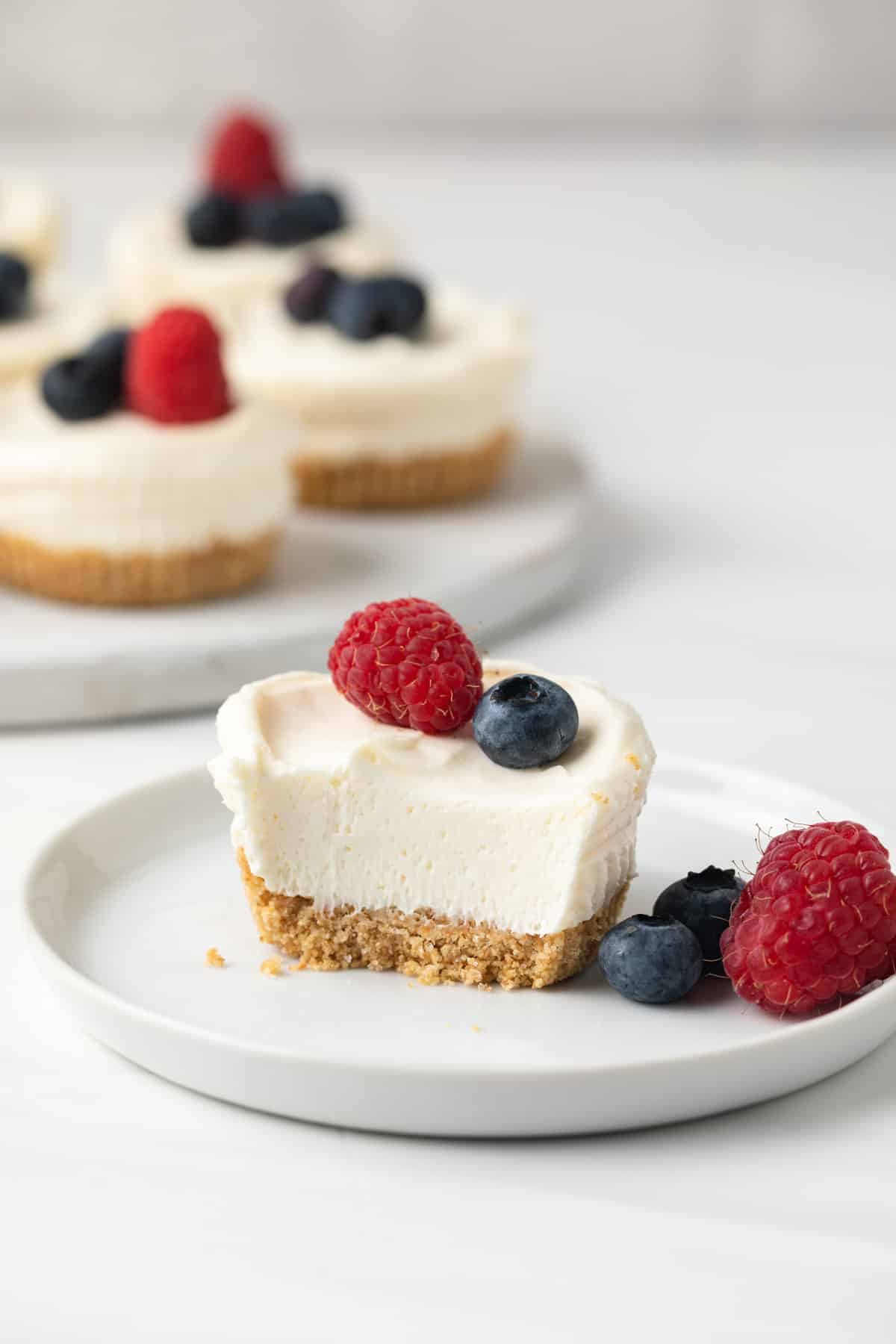 No bake mini cheesecake on plate with a bite missing.
