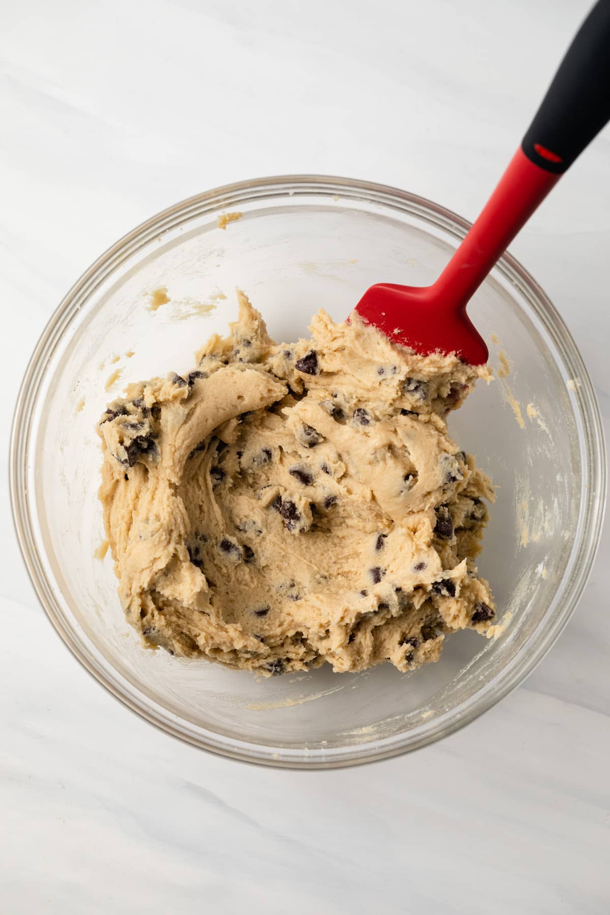 Cookie dough in glass bowl with spatula.