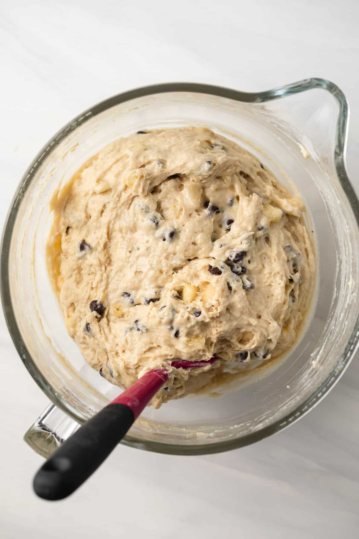 Banana chocolate chip muffin batter in glass mixing bowl.