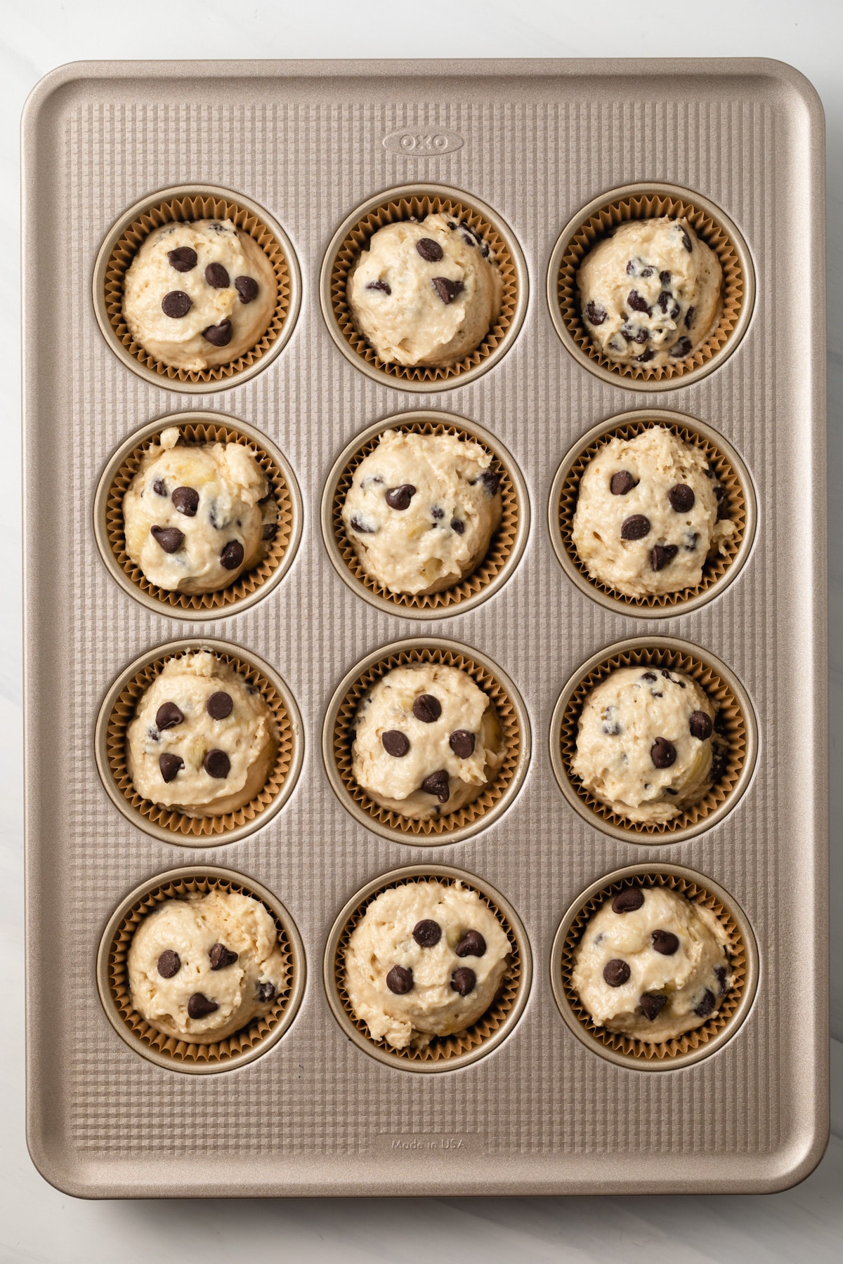 Unbaked banana chocolate chip muffins in muffin pan.