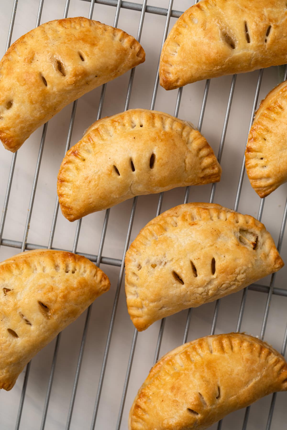 Mini apple pies on a wire rack.