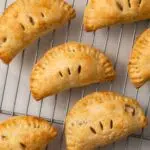 Mini apple pies on a wire rack.