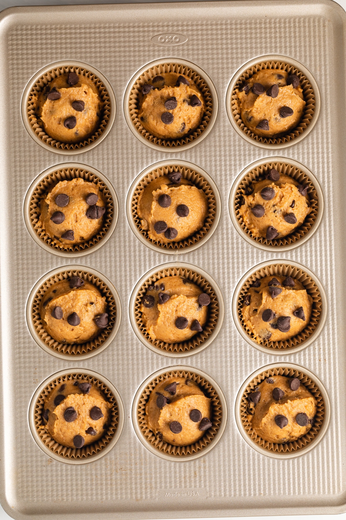 Unbaked pumpkin chocolate chip muffins in a muffin pan.