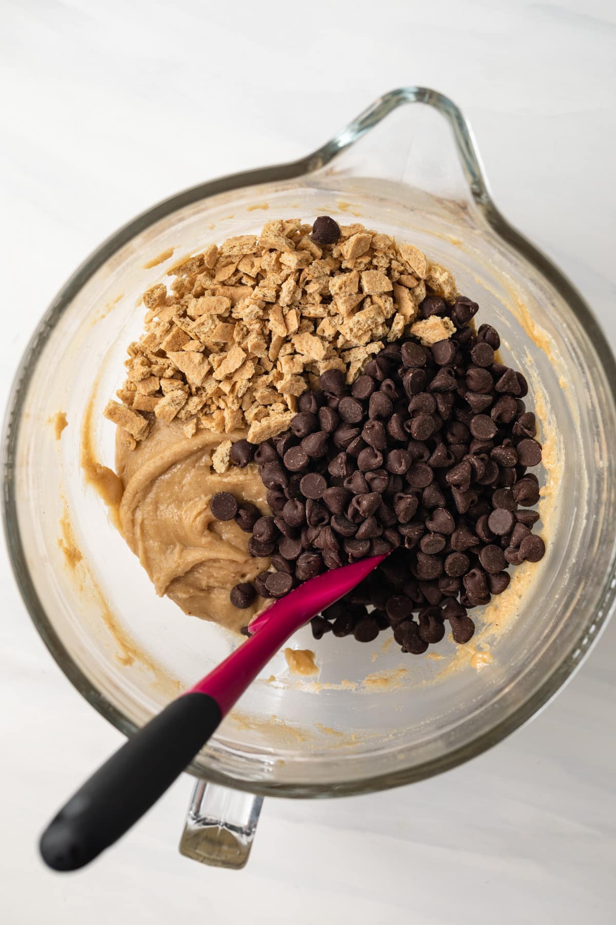 Cookie dough with chocolate chips and graham cracker pieces in glass bowl.