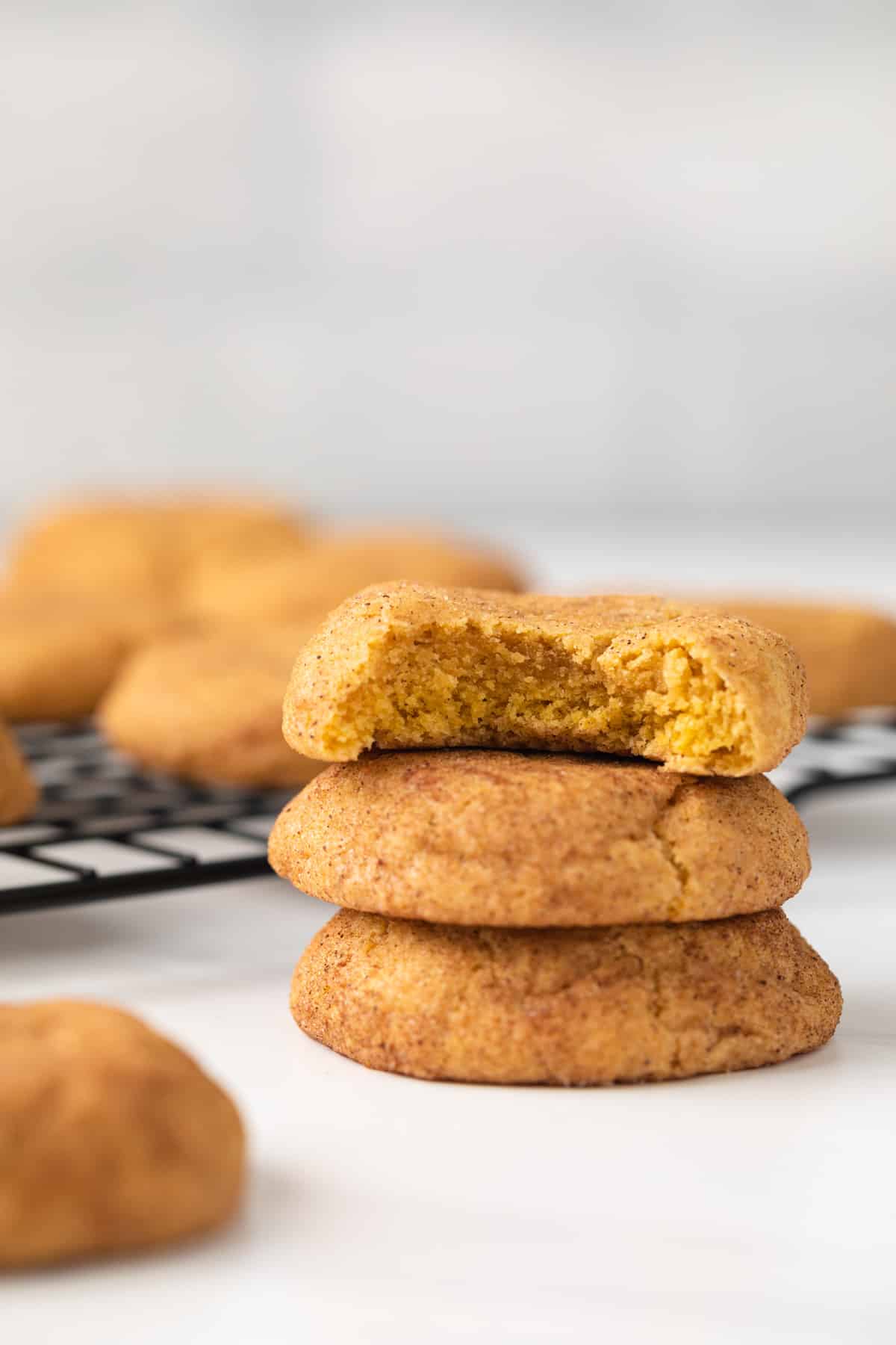 The pumpkin snickerdoodles stacked with a bite taken out of one.