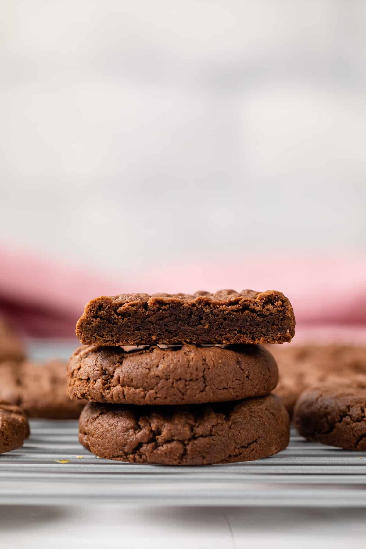 Chocolate peanut butter cookies stacked on wire rack.