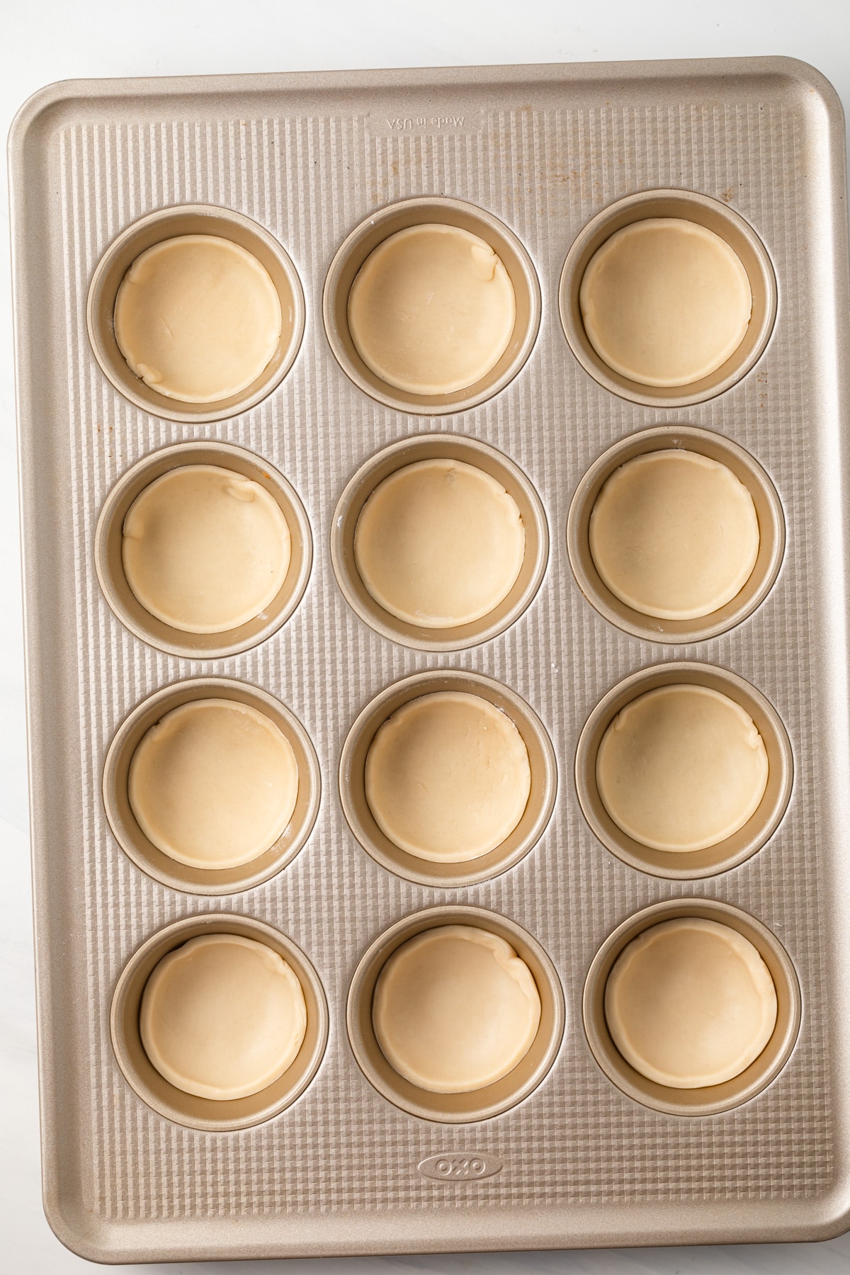 Pie dough circles pressed into muffin pan.
