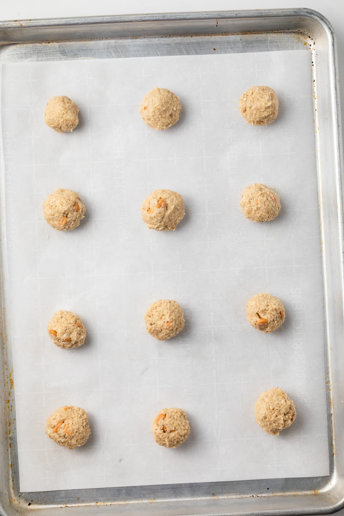 Oatmeal scotchie cookie dough balls on baking pan.