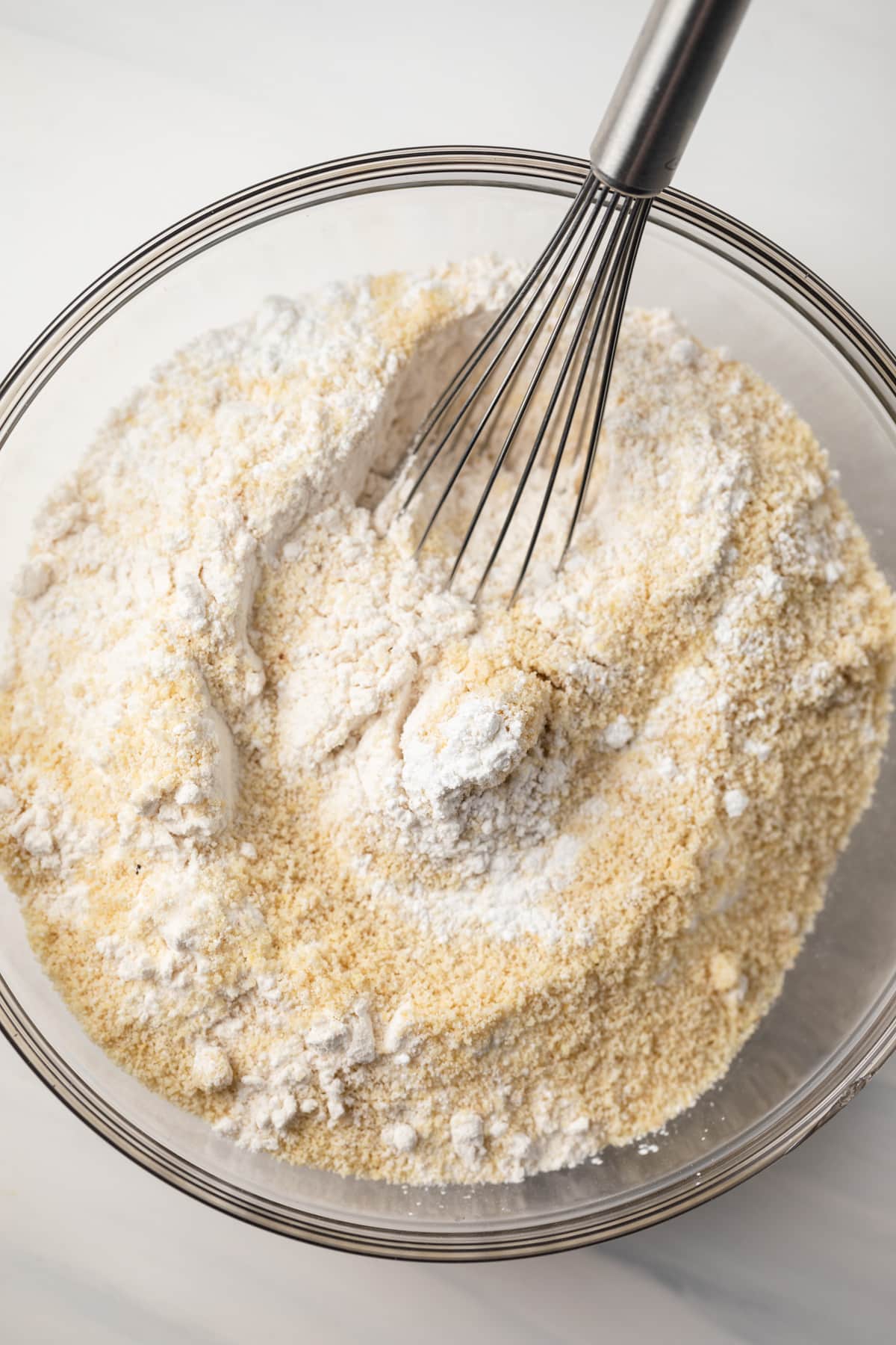 Flour and almond flour in bowl with whisk.