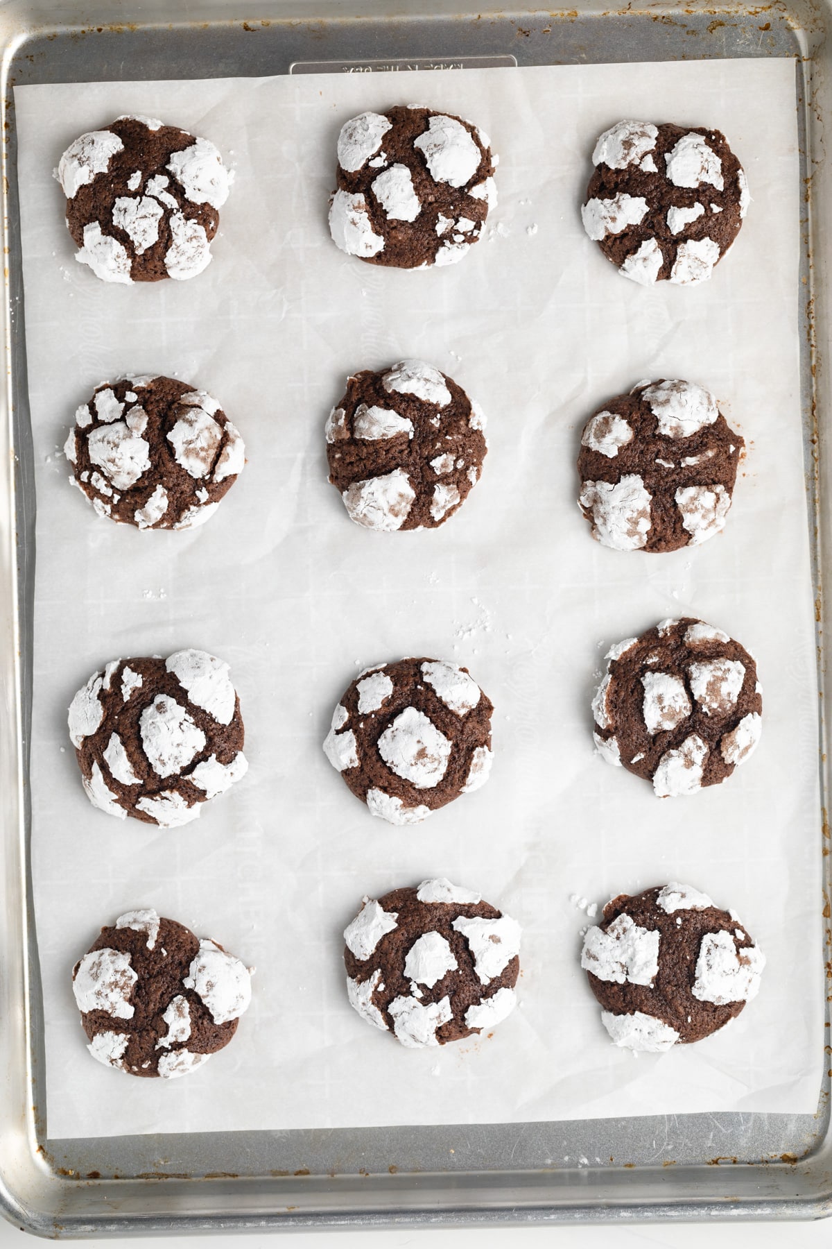 Overhead of chocolate crinkle cookies on baking sheet.