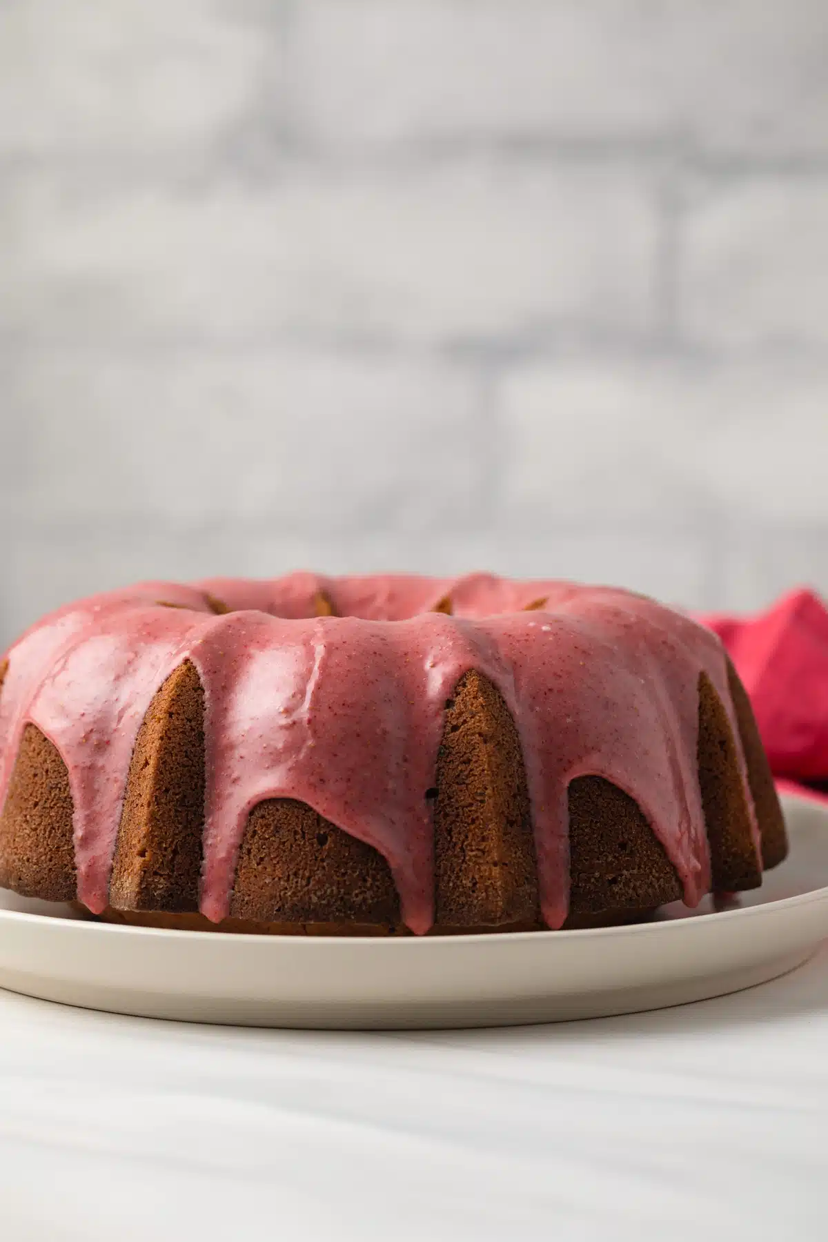 Side view of strawberry pound cake on white cake plate.