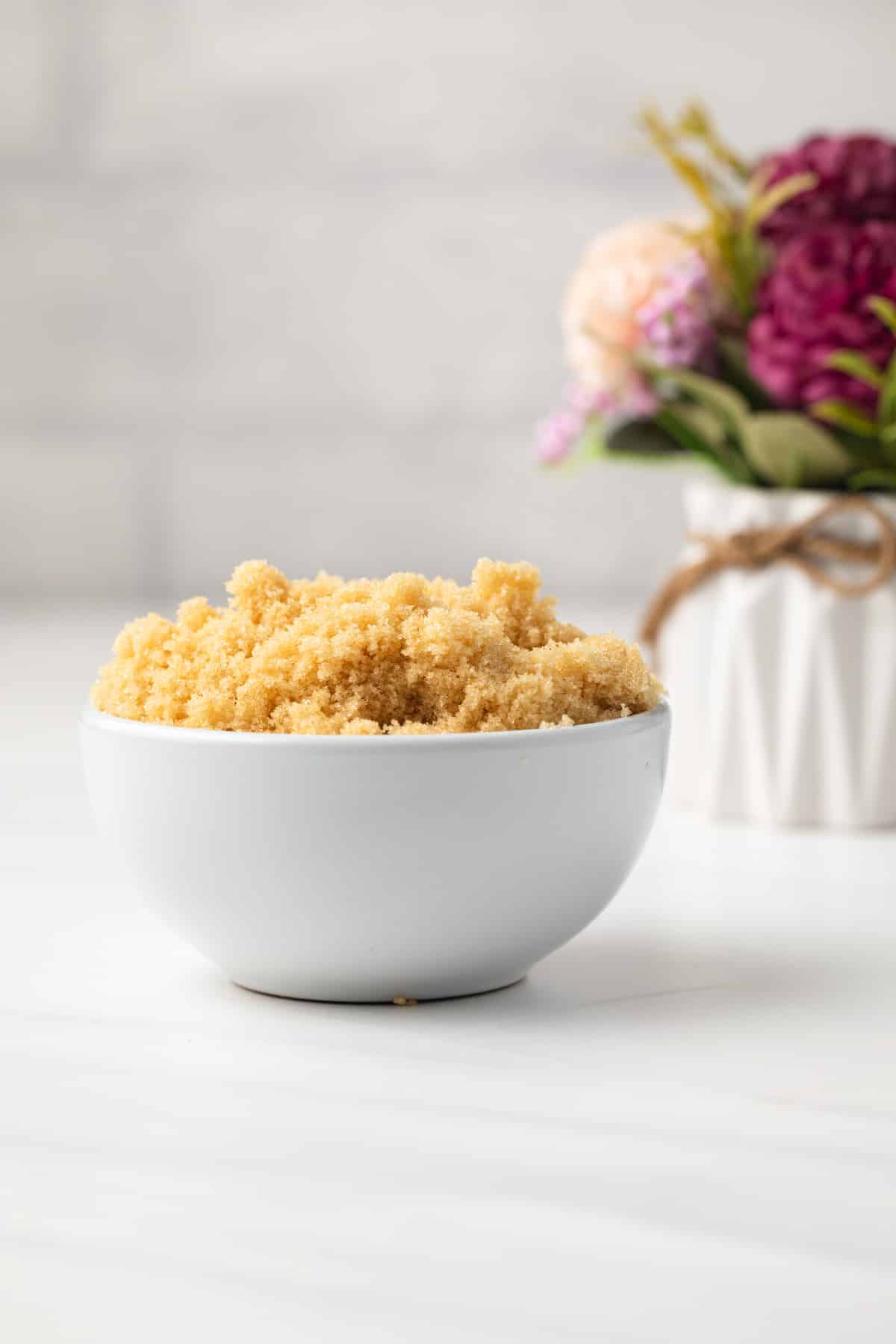 Side view of homemade brown sugar in white bowl.