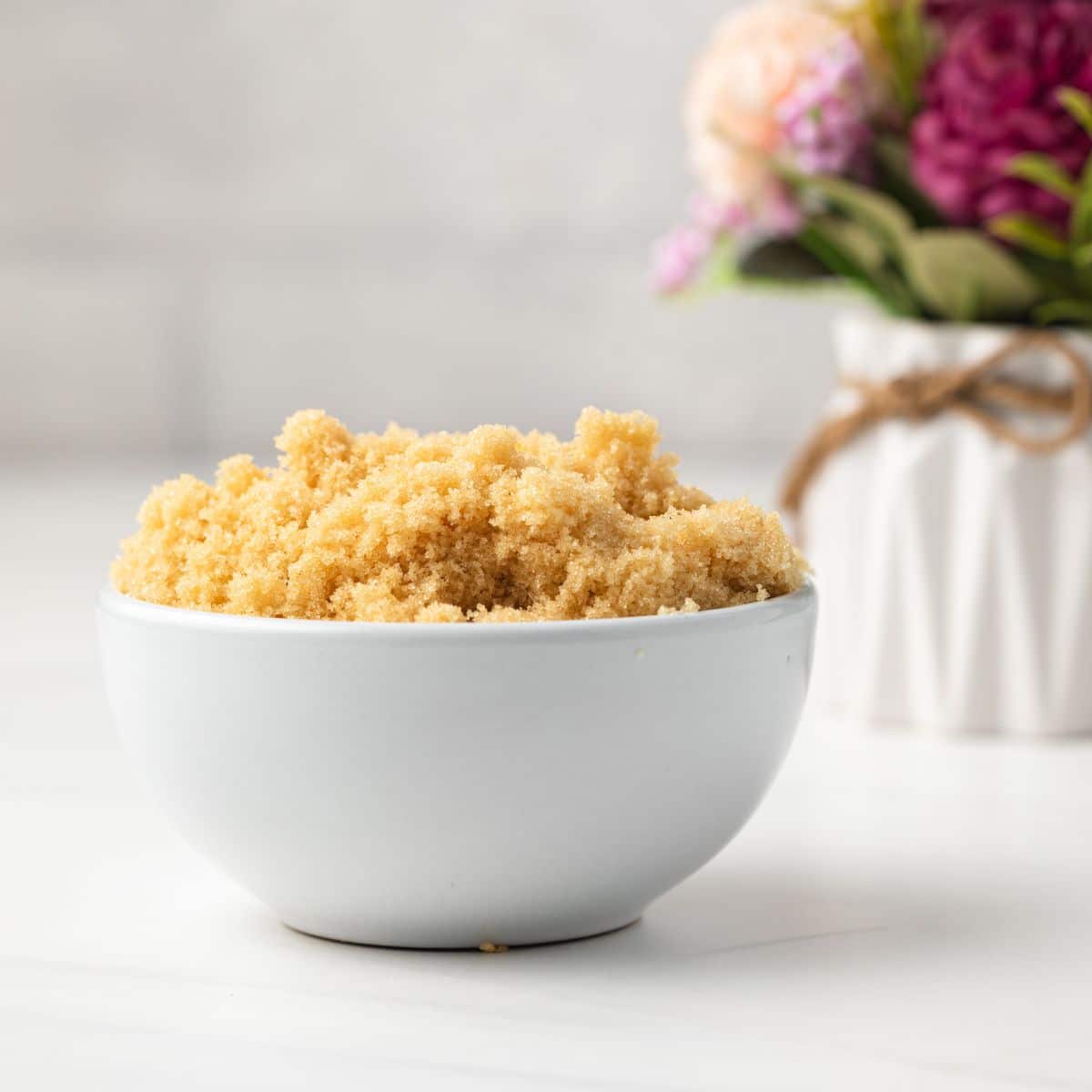 Side view of homemade brown sugar in white bowl.