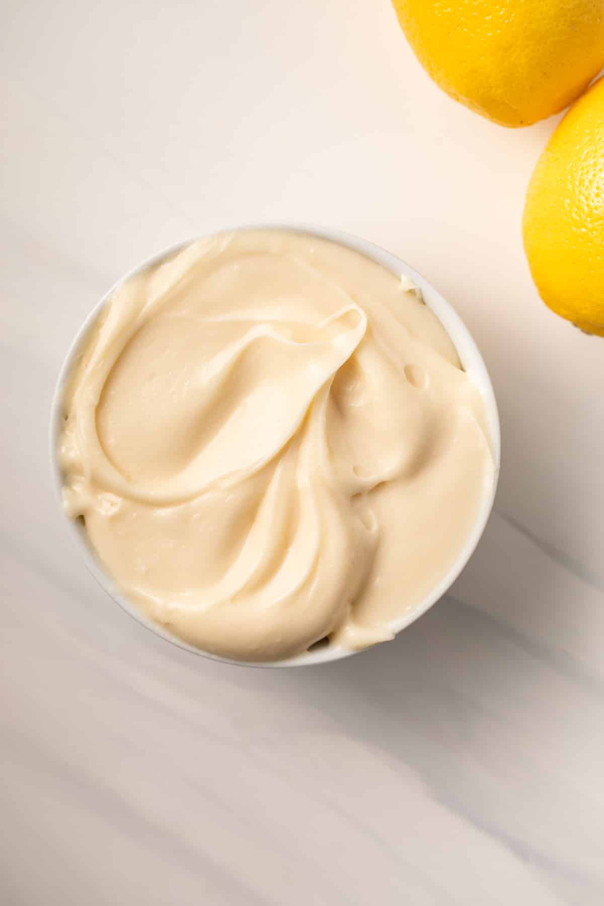 Lemon cream cheese frosting in white bowl.