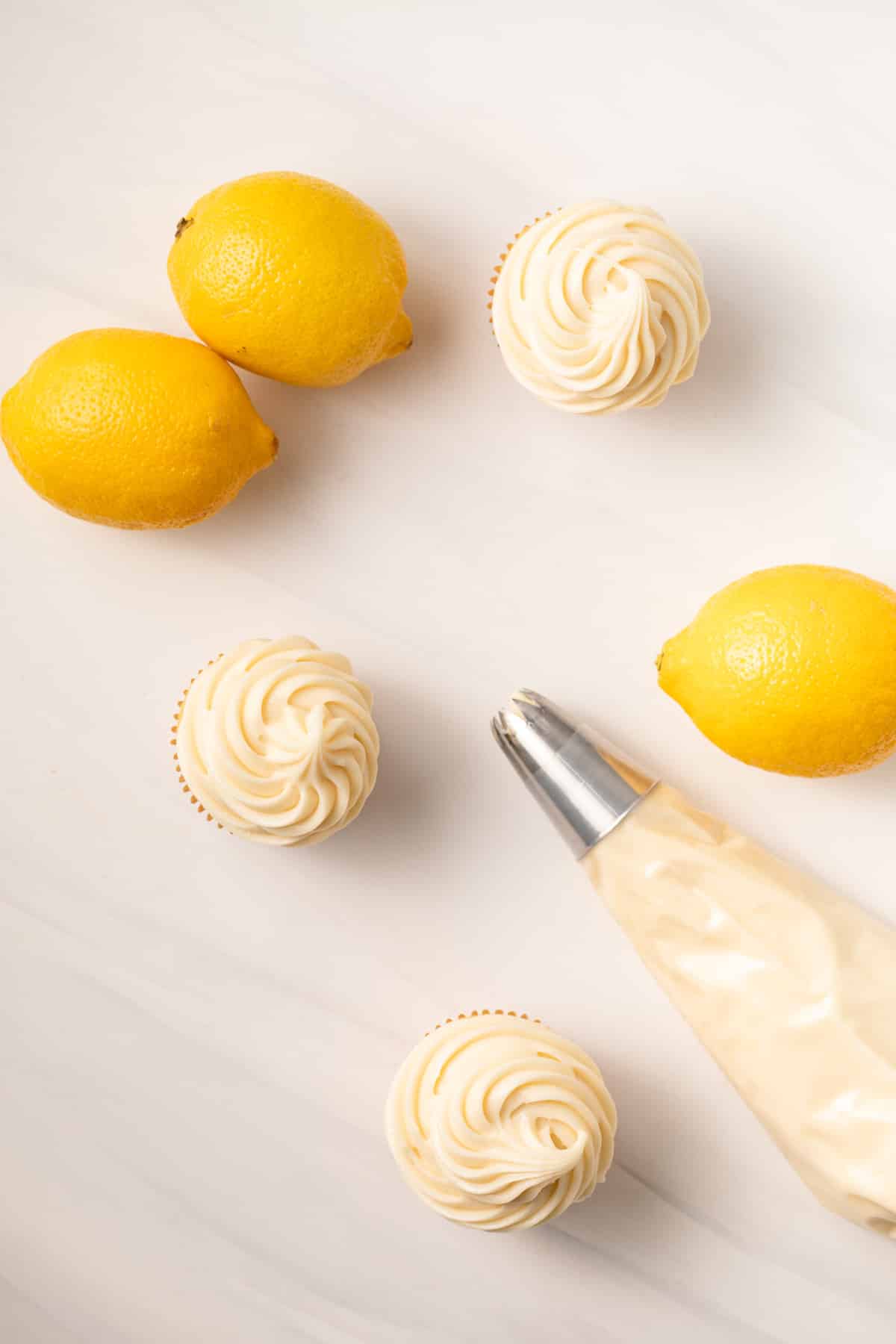 Overhead of lemon cream cheese frosting pipped on top of vanilla cupcakes.