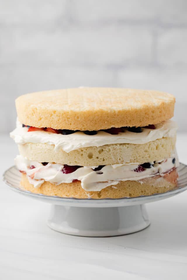 Naked chantilly cake on a cake stand.