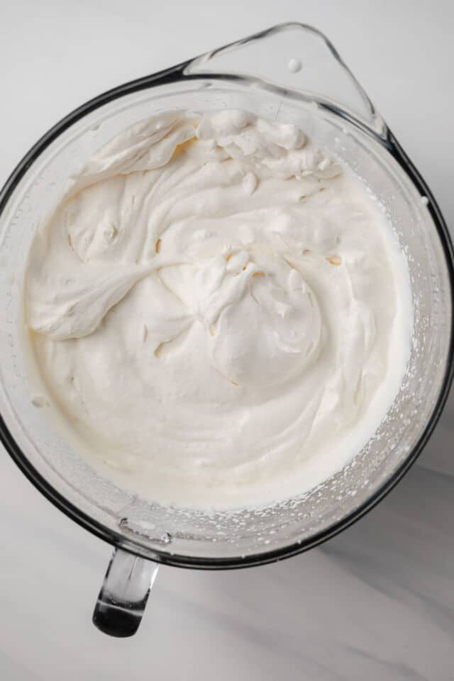 Whipped cream in a glass mixing bowl.