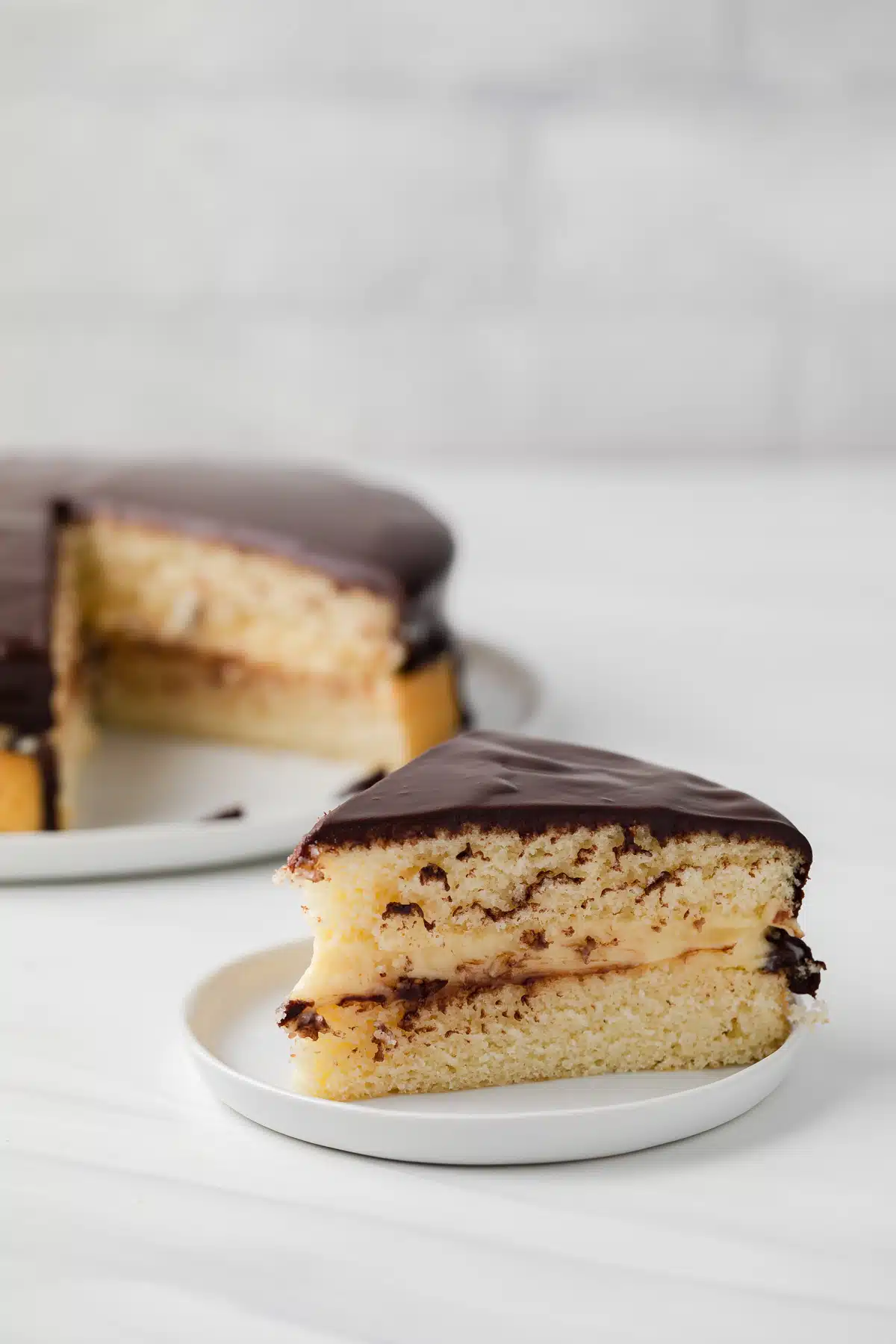 Slice of boston cream pie on white plate.