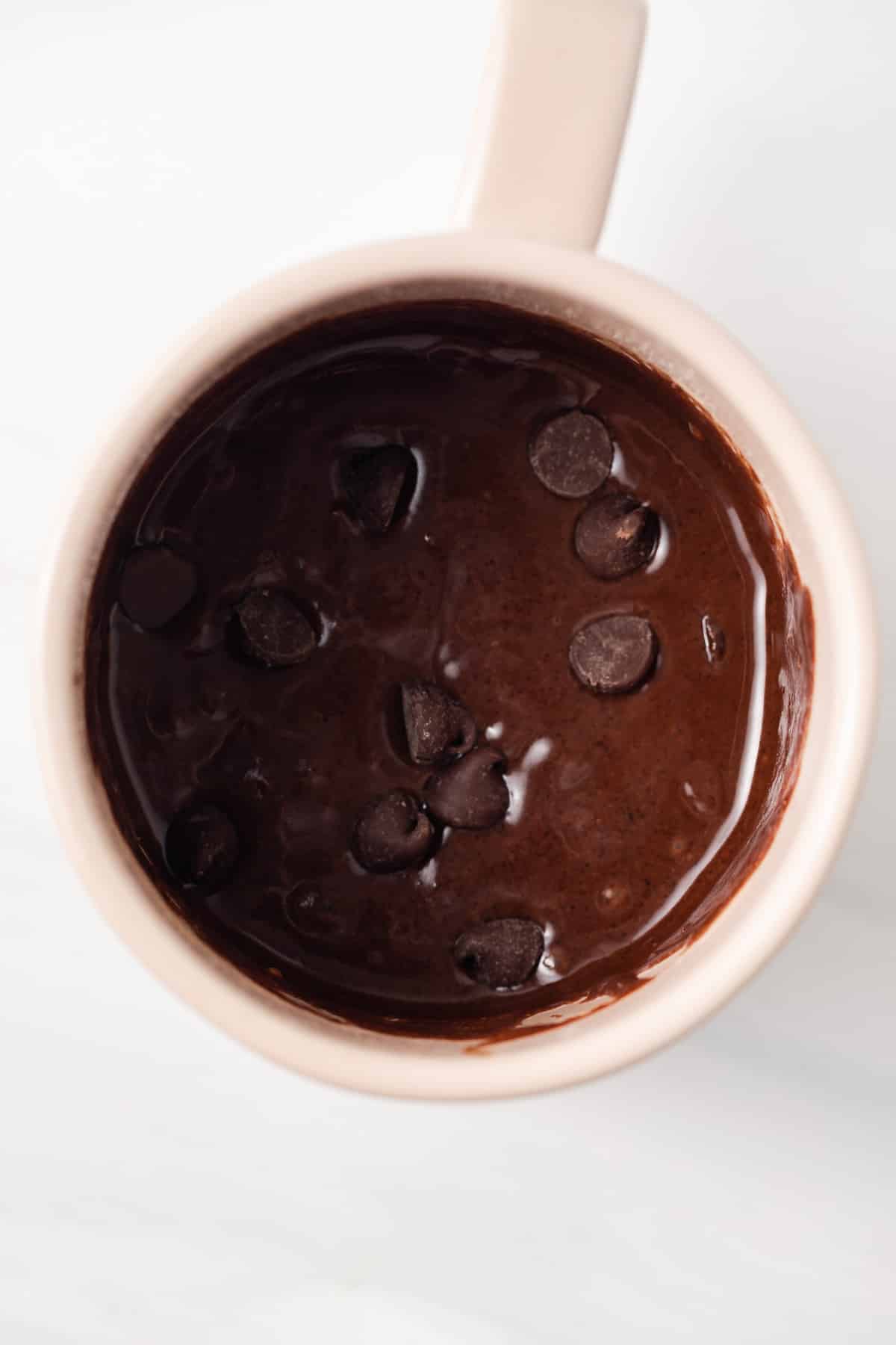 Brownie batter in a mug with chocolate chips.