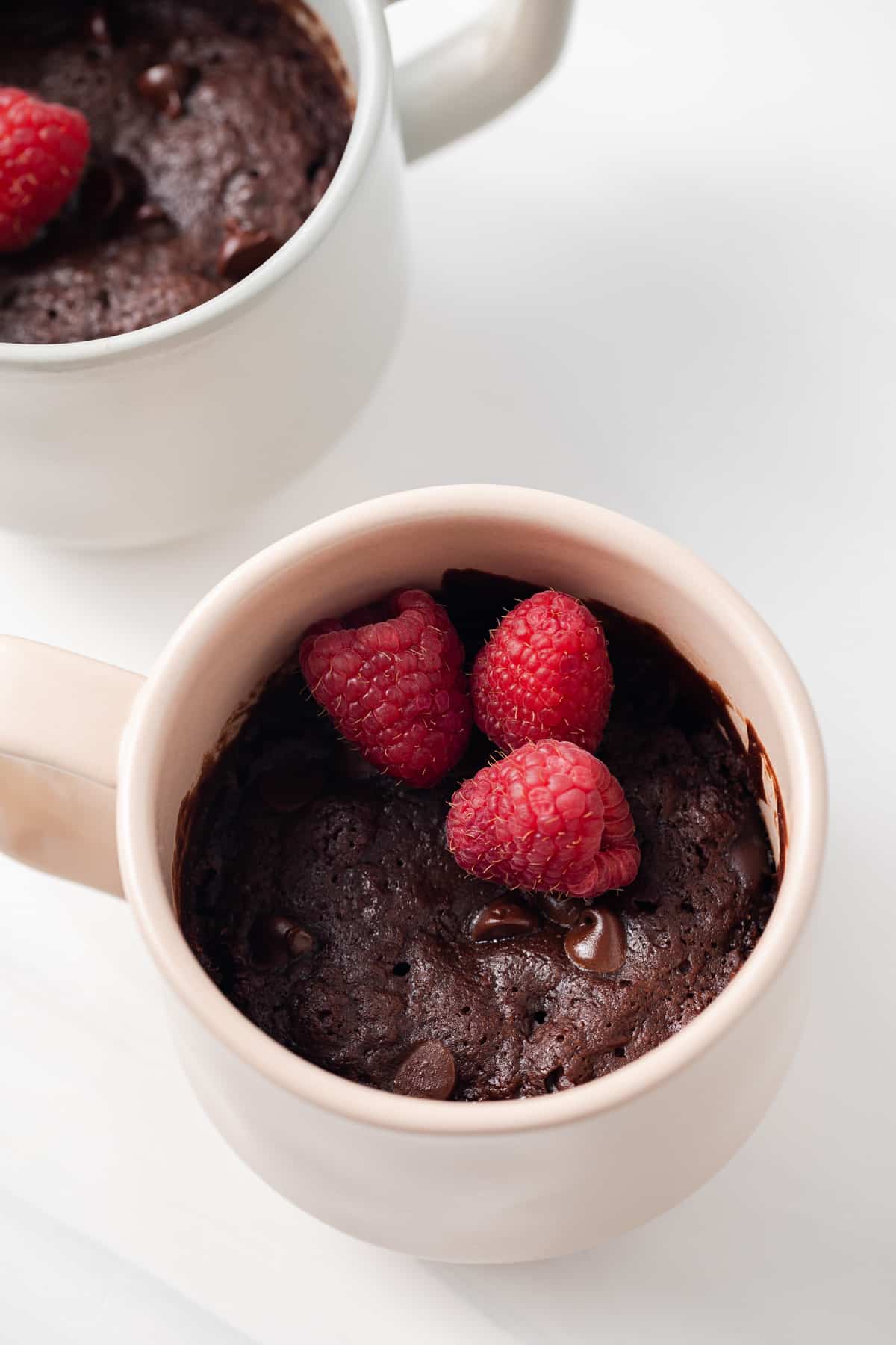 Brownie in a mug topped with raspberries.