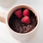 Brownie in a mug topped with raspberries.