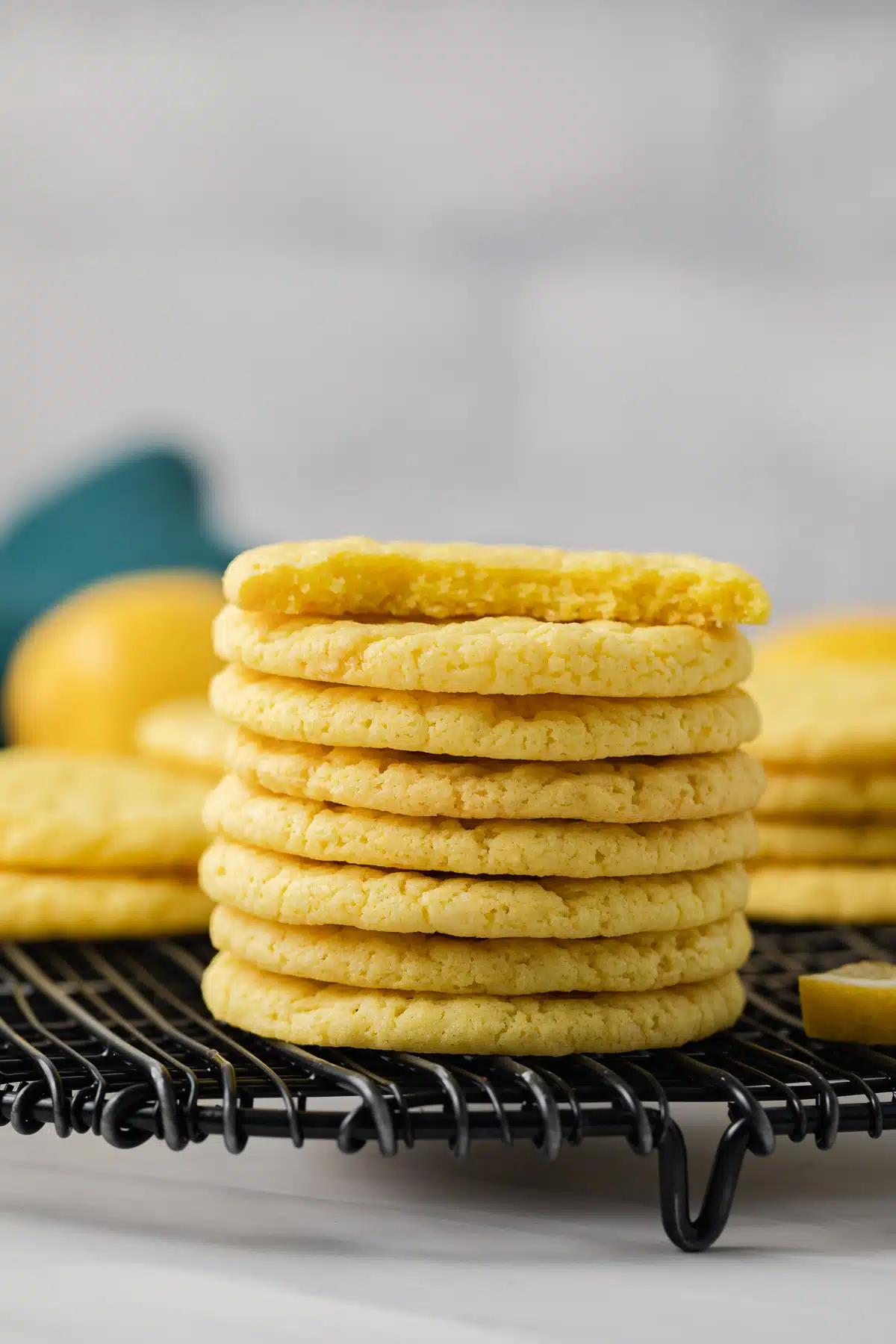 Lemon cookies stacked on wire rack.